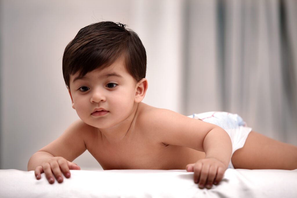 Toddler photography Auckland session of cute baby looking down on white bed