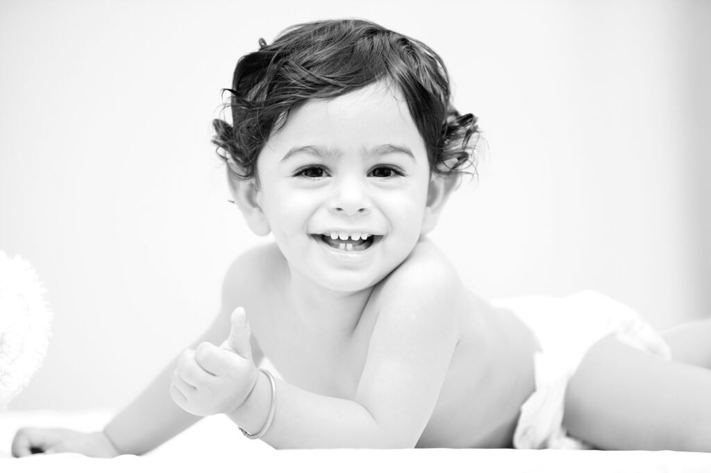 Infant photography Auckland session of smiling baby doing thumbs up gesture