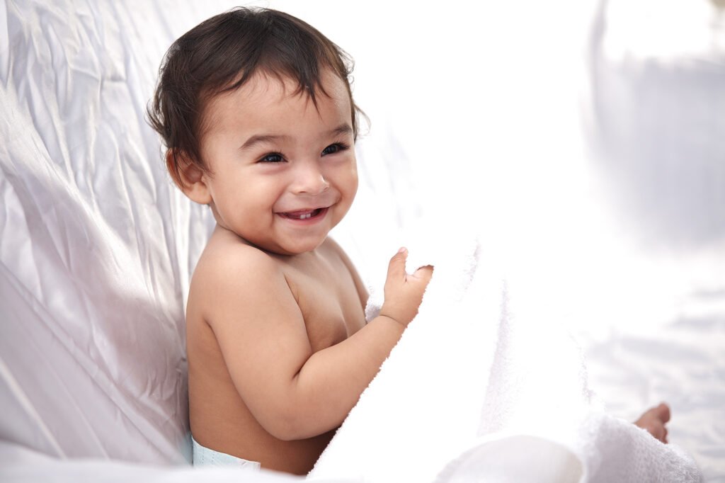 Toddler photography Auckland session of smiling baby boy holding white towel