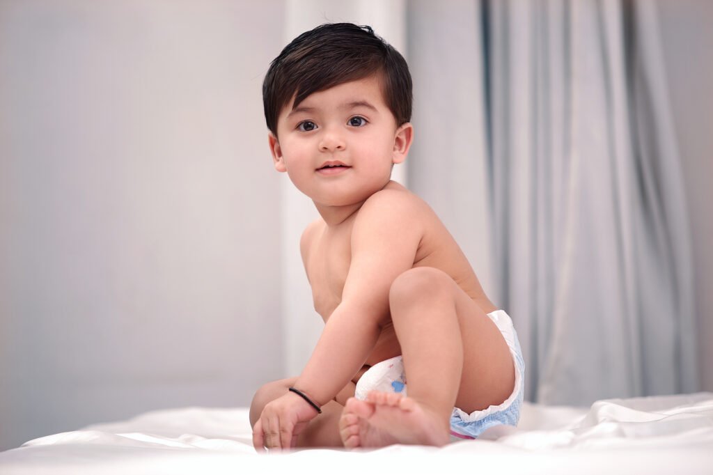 Baby photographer Auckland studio session of cute toddler sitting on white bed