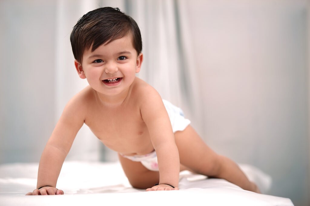 Baby photography Auckland session of smiling infant crawling on white bed