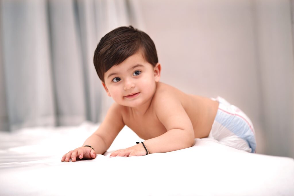 Baby photographer Auckland session of cute infant in diaper crawling on bed