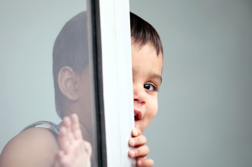 Kids portrait photography Auckland session of toddler peeking behind glass door