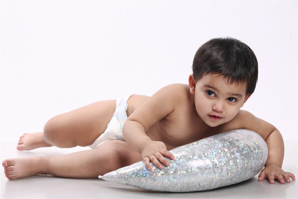 Infant photographer Auckland studio session of cute baby holding silver glitter prop