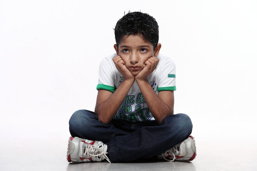 Childrens portrait photography Auckland session of thoughtful boy sitting cross legged