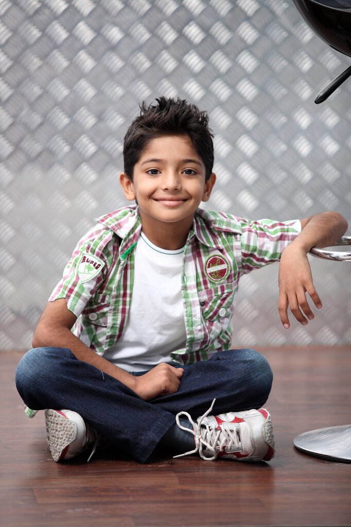 Kids portrait photography Auckland session of smiling boy sitting cross legged on floor