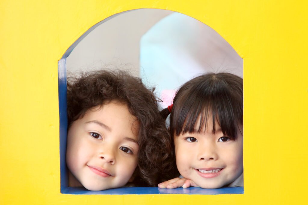 Family and child photography Auckland session of smiling children looking through yellow window