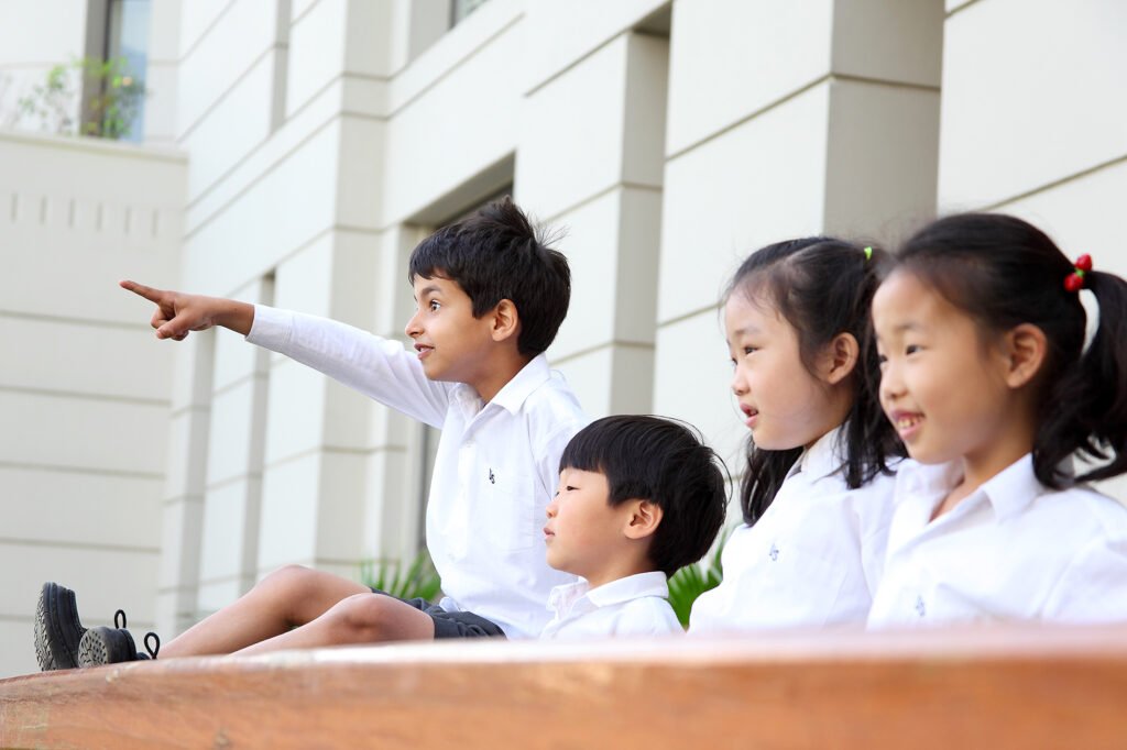 School advertising photography Auckland of kids pointing in uniform shirts