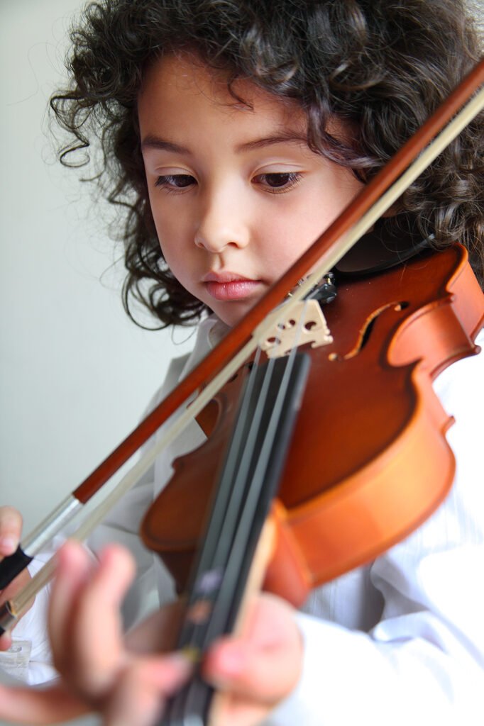 School campaign photography Auckland of young child playing violin