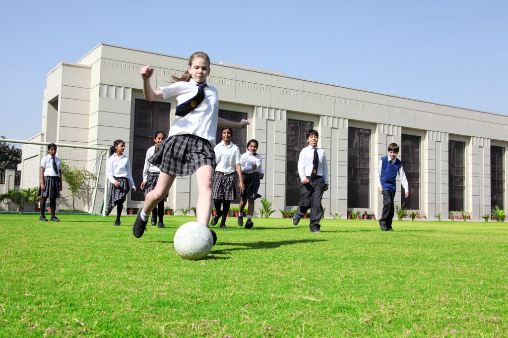 School commercial photography Auckland of girl student kicking football on field