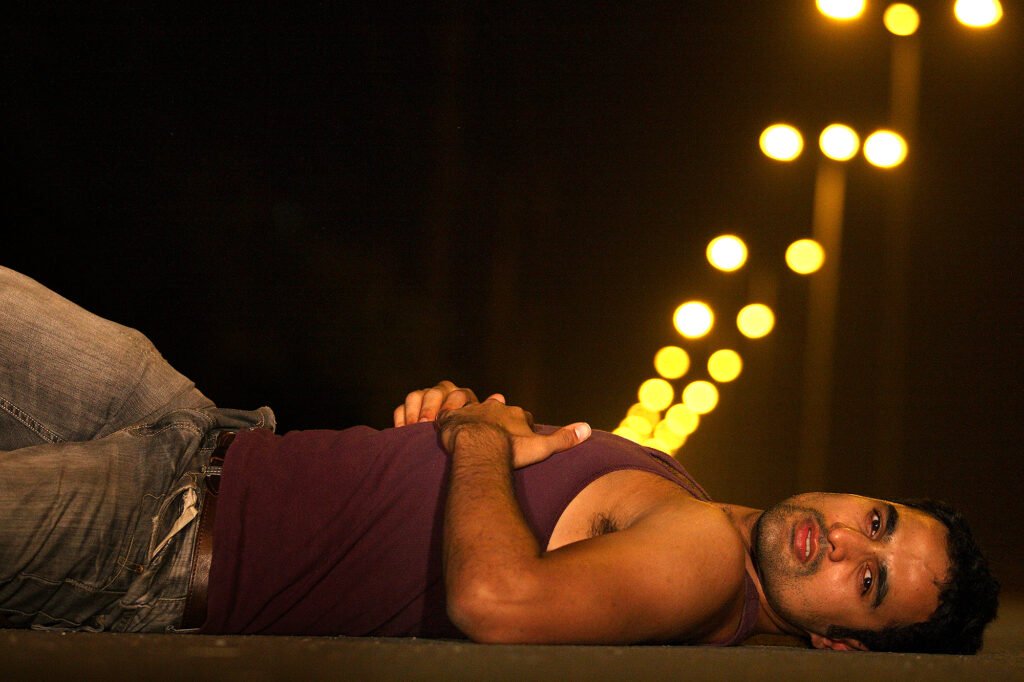 Australian actor Nicholas Brown lying down during an outdoor cinematic night portrait shoot with street bokeh lights by Auckland photographer Jassa Studio